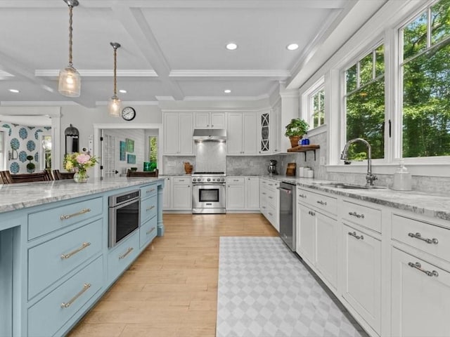 35 Forster Rd, Manchester, MA 01944 - kitchen featuring appliances with stainless steel finishes, white cabinets, under cabinet range hood, light wood-style floors, and decorative backsplash