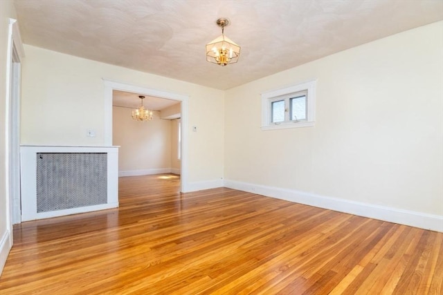 57 Ardale St, Boston, MA 02131 - empty room featuring a chandelier, light wood-type flooring, baseboards, and radiator