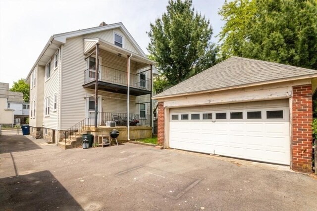 57 Ardale St, Boston, MA 02131 - view of front of property featuring a balcony, an outdoor structure, brick siding, a detached garage, and a shingled roof