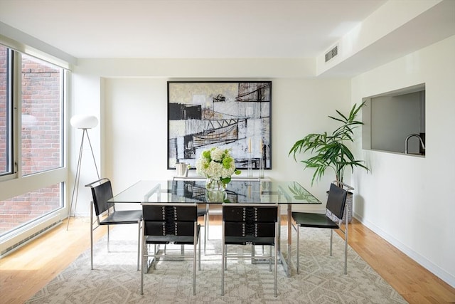 dining area with wood finished floors, visible vents, and baseboards