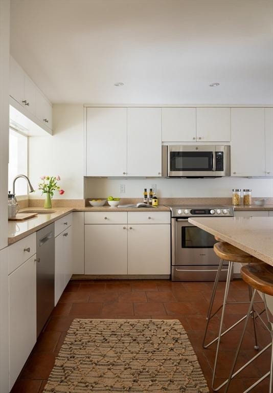 kitchen with a sink, light countertops, white cabinets, and stainless steel appliances
