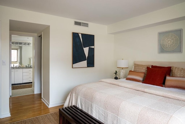 bedroom with wood finished floors, visible vents, and baseboards