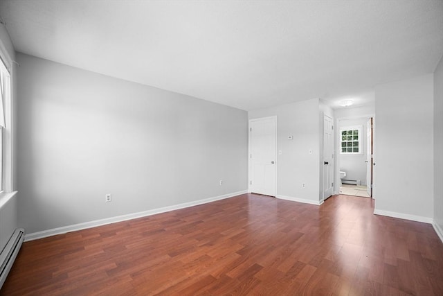 spare room with baseboards, baseboard heating, and dark wood-style floors