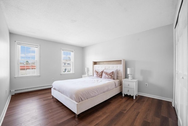 bedroom featuring baseboards, a baseboard heating unit, and dark wood finished floors