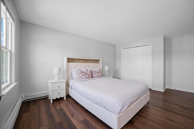 bedroom with dark wood-type flooring, a baseboard heating unit, baseboard heating, and a closet