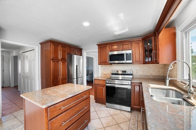 kitchen featuring a sink, appliances with stainless steel finishes, light tile patterned floors, and backsplash