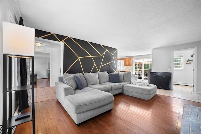 living area featuring light wood-style floors, a baseboard radiator, and an accent wall