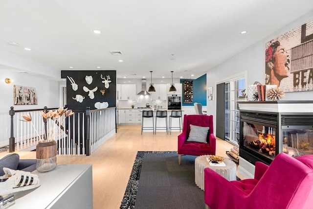 living area featuring light wood finished floors, visible vents, recessed lighting, and a multi sided fireplace