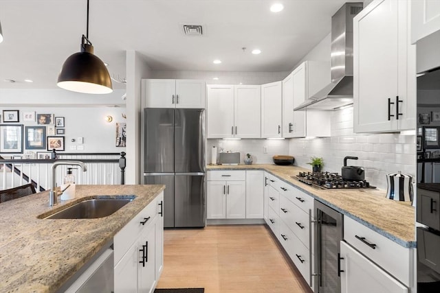 kitchen with visible vents, a sink, wine cooler, appliances with stainless steel finishes, and wall chimney exhaust hood