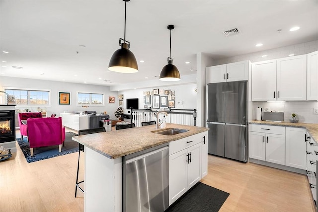 kitchen featuring visible vents, a sink, white cabinets, appliances with stainless steel finishes, and open floor plan