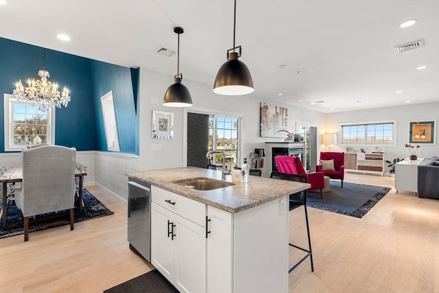 kitchen featuring stainless steel dishwasher, light wood-style flooring, visible vents, and a sink