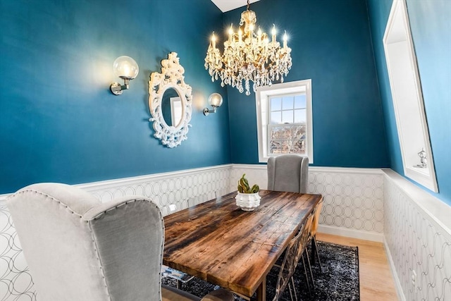 dining room with a chandelier, wood finished floors, and wainscoting