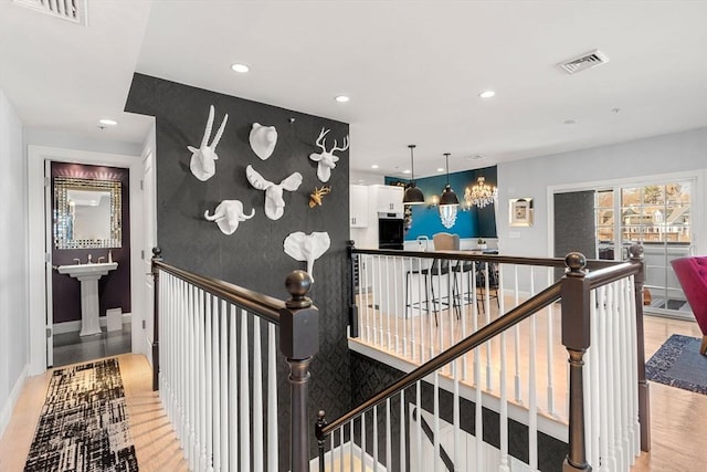 corridor featuring an upstairs landing, visible vents, recessed lighting, and light wood-style floors