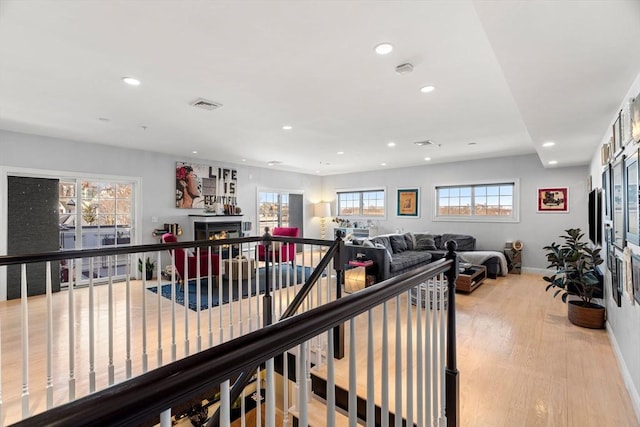 interior space featuring visible vents, baseboards, recessed lighting, light wood-style floors, and an upstairs landing