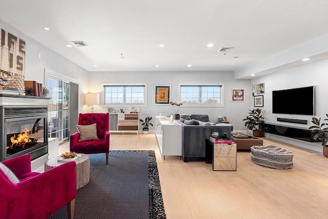 living room featuring recessed lighting, wood finished floors, visible vents, and a multi sided fireplace