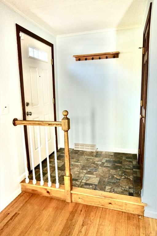 staircase featuring baseboards, wood finished floors, visible vents, and ornamental molding