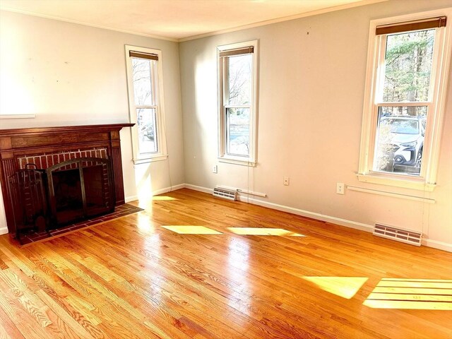 unfurnished living room with a wealth of natural light, visible vents, baseboards, and wood finished floors