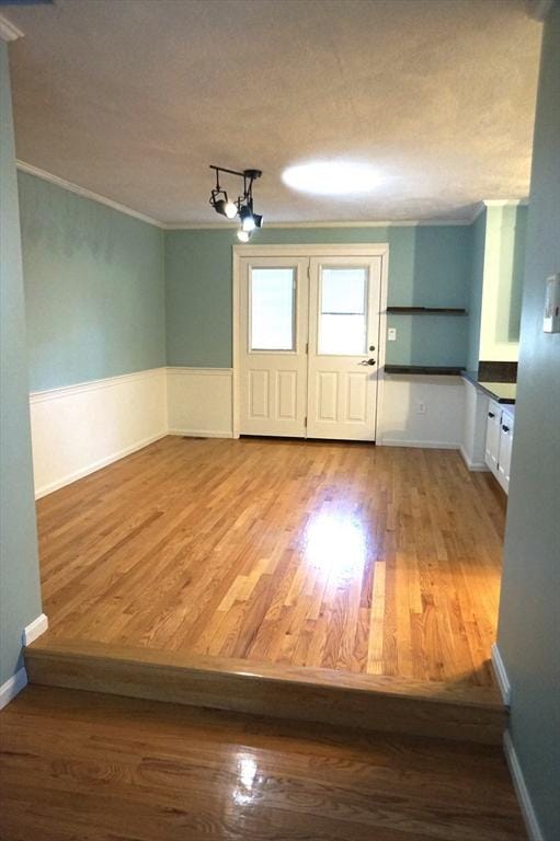 interior space featuring a textured ceiling, wood finished floors, and crown molding