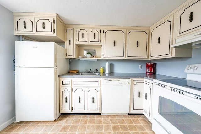 kitchen featuring white appliances, a sink, cream cabinetry, and baseboards