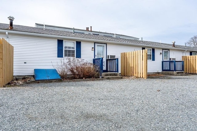 rear view of property featuring driveway and fence