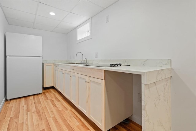 kitchen with sink, white refrigerator, kitchen peninsula, a drop ceiling, and light wood-type flooring