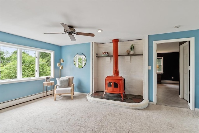 82 Powow St, Amesbury, MA 01913 - sitting room featuring a baseboard radiator, a wood stove, carpet, and a ceiling fan