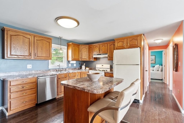 82 Powow St, Amesbury, MA 01913 - kitchen with white appliances, under cabinet range hood, dark wood-type flooring, a kitchen bar, and pendant lighting