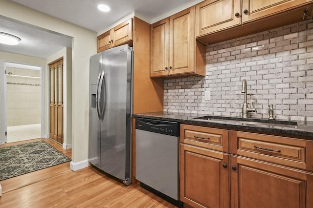 9 Broadway Unit 217, Saugus, MA 01906 - kitchen featuring stainless steel appliances, a sink, backsplash, light wood finished floors, and brown cabinetry