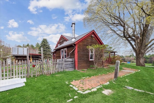 view of home's exterior with a lawn and fence