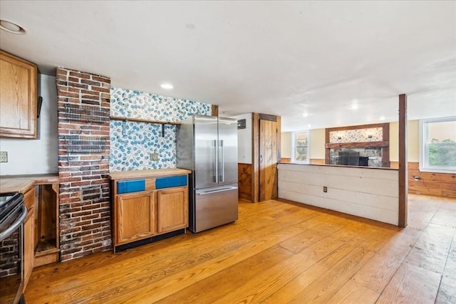 kitchen with brown cabinets, a fireplace, stainless steel appliances, and light wood finished floors
