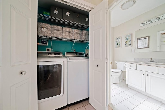 washroom featuring independent washer and dryer, sink, and light tile patterned floors