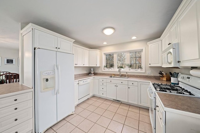 kitchen with light tile patterned flooring, white appliances, white cabinetry, and sink