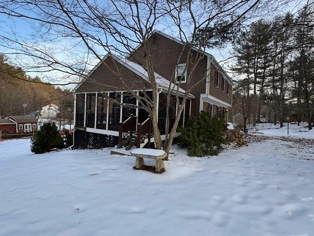 snow covered house featuring a sunroom