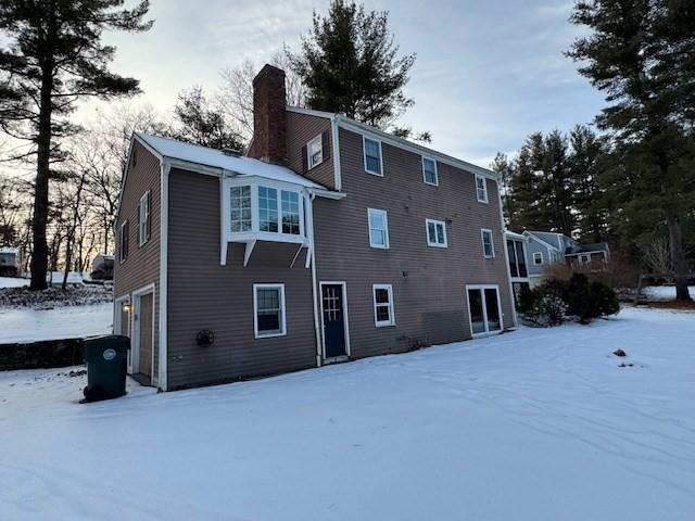 snow covered rear of property with a garage