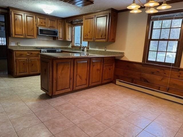 kitchen with a baseboard radiator, hanging light fixtures, kitchen peninsula, a healthy amount of sunlight, and a textured ceiling