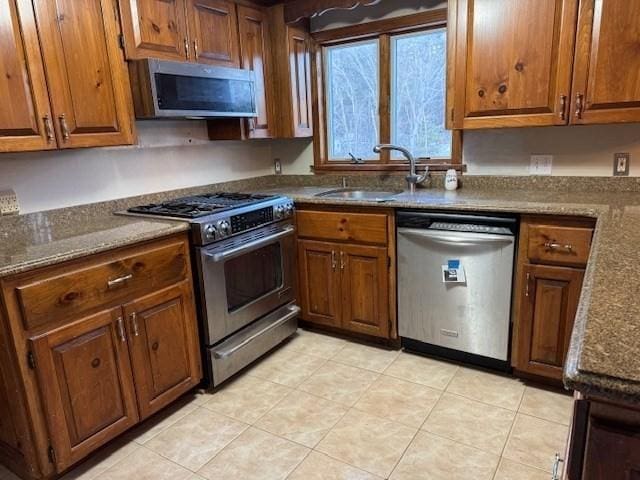 kitchen with appliances with stainless steel finishes, sink, and dark stone countertops