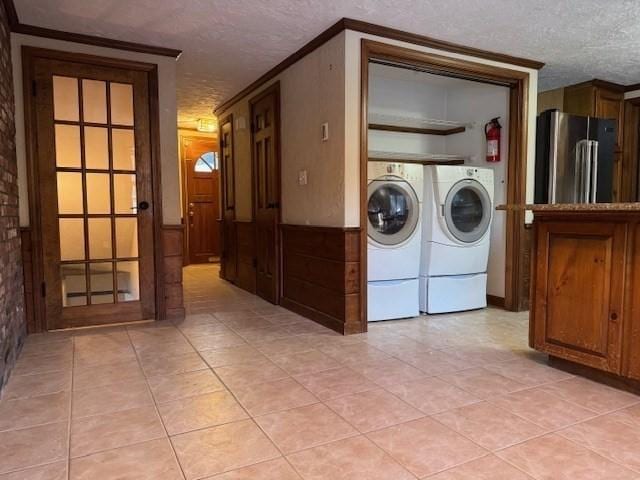 laundry area featuring separate washer and dryer, light tile patterned floors, crown molding, and a textured ceiling