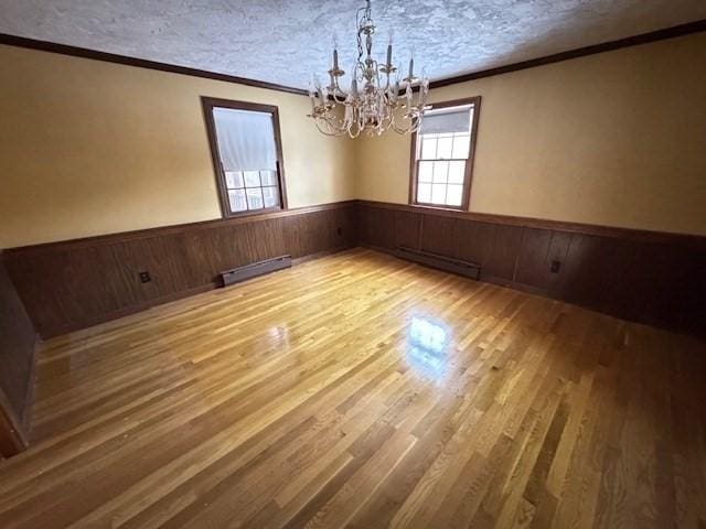 unfurnished dining area with baseboard heating, a textured ceiling, and hardwood / wood-style flooring