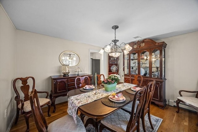 dining area featuring dark wood finished floors, visible vents, a baseboard heating unit, and an inviting chandelier