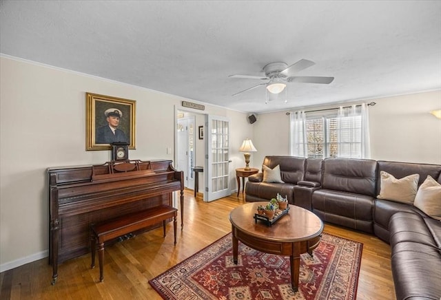 living area with baseboards, a textured ceiling, ceiling fan, and light wood finished floors