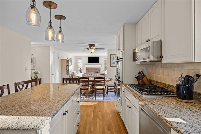 kitchen featuring stainless steel appliances, light wood-style floors, white cabinets, and decorative backsplash