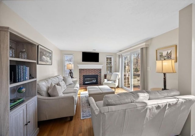 living area with a brick fireplace and dark wood-style flooring