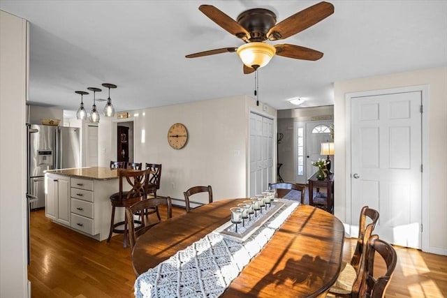 dining area with ceiling fan, a baseboard heating unit, baseboards, and wood finished floors