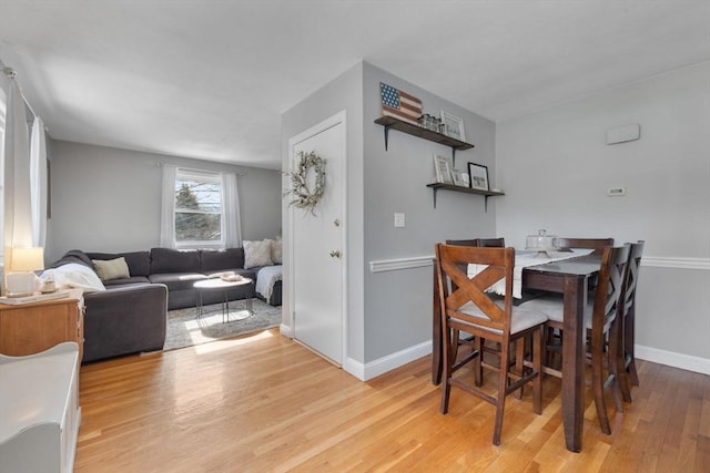 dining space with light wood-style flooring and baseboards