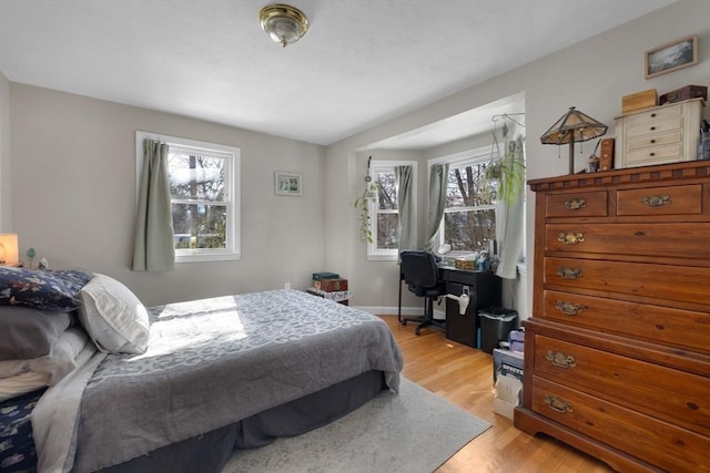 bedroom with multiple windows, light wood-style flooring, and baseboards