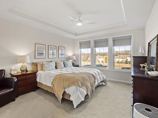 carpeted bedroom with ceiling fan, ornamental molding, and a raised ceiling