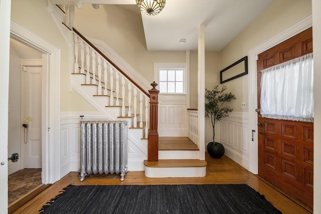 1 Murdock Ter, Boston, MA 02135 - entrance foyer with radiator heating unit, a decorative wall, wood finished floors, wainscoting, and stairway