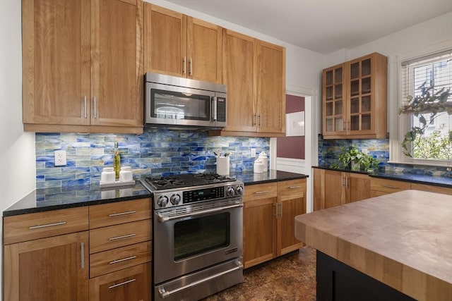 1 Murdock Ter, Boston, MA 02135 - kitchen with stainless steel appliances, glass insert cabinets, decorative backsplash, dark stone counters, and brown cabinetry