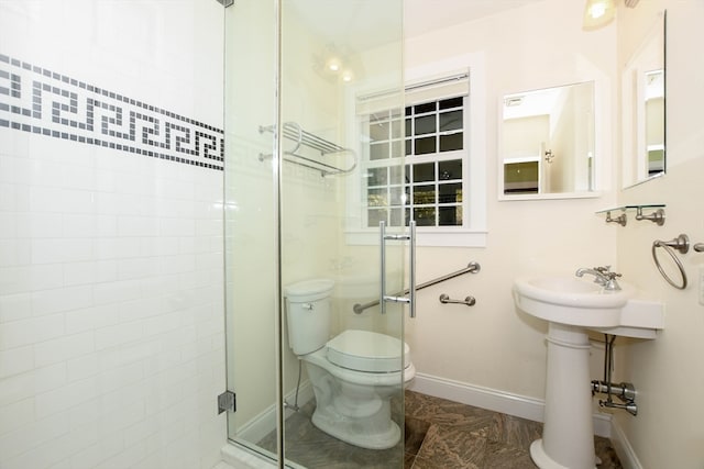 bathroom with a shower with door, sink, and toilet