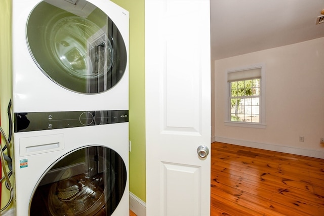 clothes washing area featuring stacked washer / drying machine and wood-type flooring